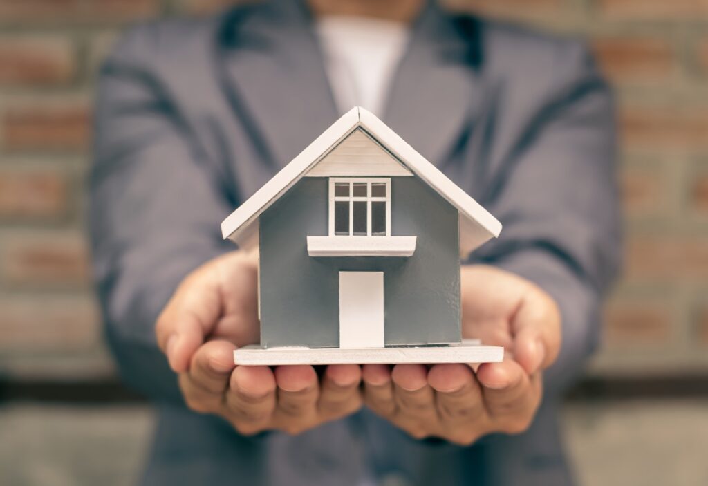 Home insurance concept and real estate. Businesswoman holding a house model working in investment